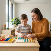 Ergotherapeutin kniet neben einem Kind beim praktischen Lernübung am Holztisch, bunte Lernmaterialien, helles Therapiezimmer.