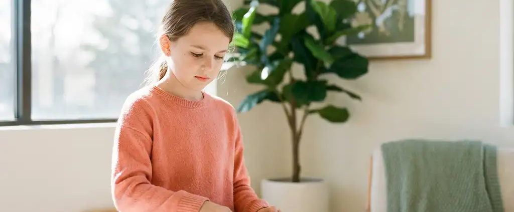 Kind beim Zusammensetzen bunter Holzpuzzleteile auf einem Therapietisch, natürliches Tageslicht, freundliche klinische Umgebung.