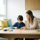 Kind arbeitet mit Therapeutin an bunten Lernmaterialien und Puzzle in hellem, modernem Therapieraum mit Eichenholztisch.